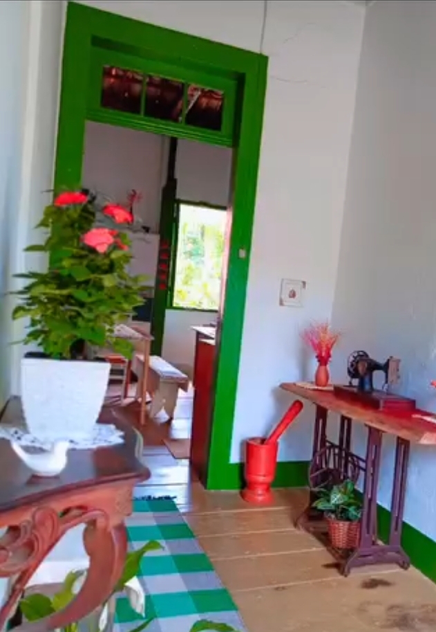 Corredor da casa principal, com flores e móveis antigos