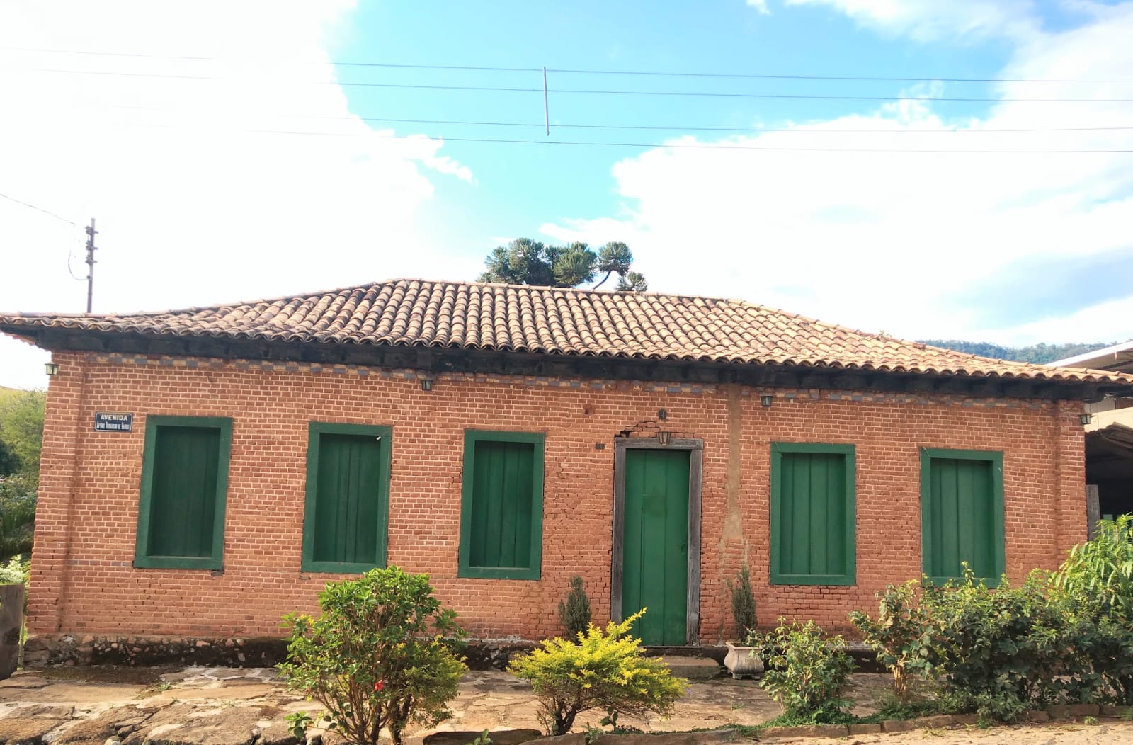 Fachada da Casa do Tijolinho, tijolo aparente com janelas verdes